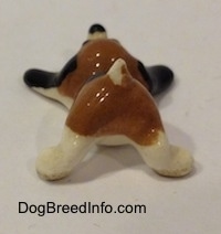 The back side of a brown with white and black Hound Dawg figurine that has its short tail in the air.